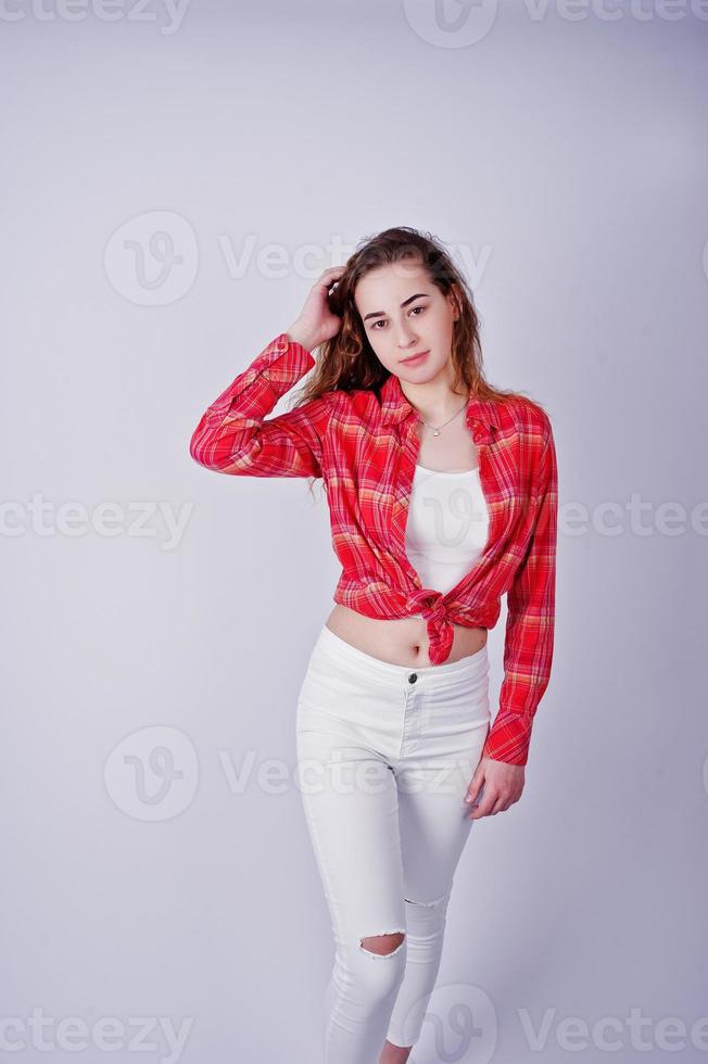 Young girl in red checked shirt and white pants against white background on studio. photo