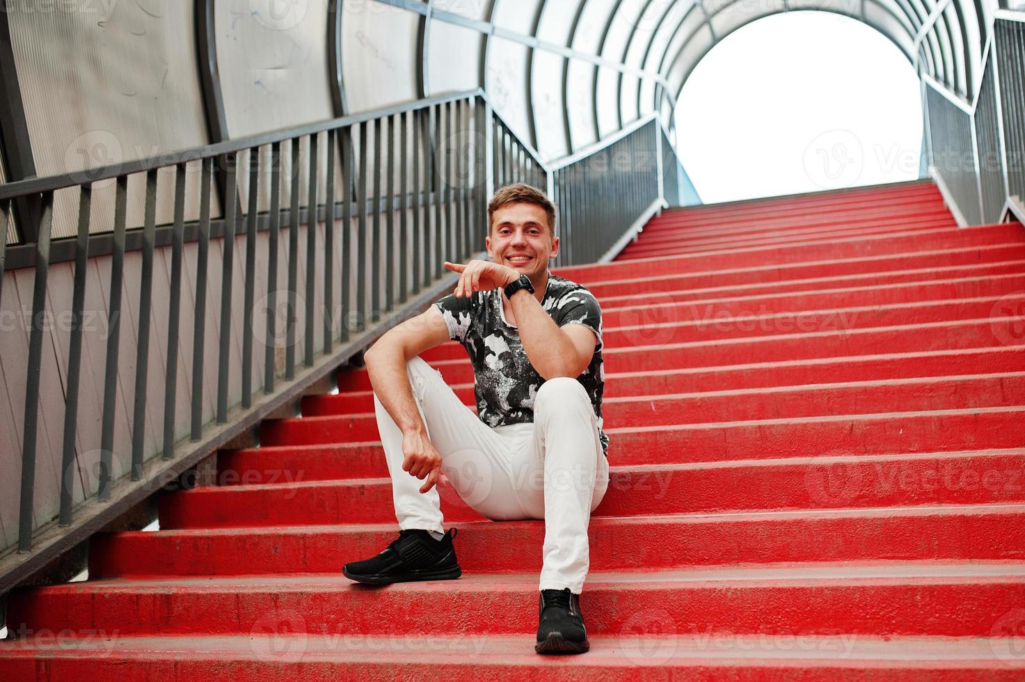 Lifestyle portrait of handsome man posing in red stairs of the city tonnel. photo