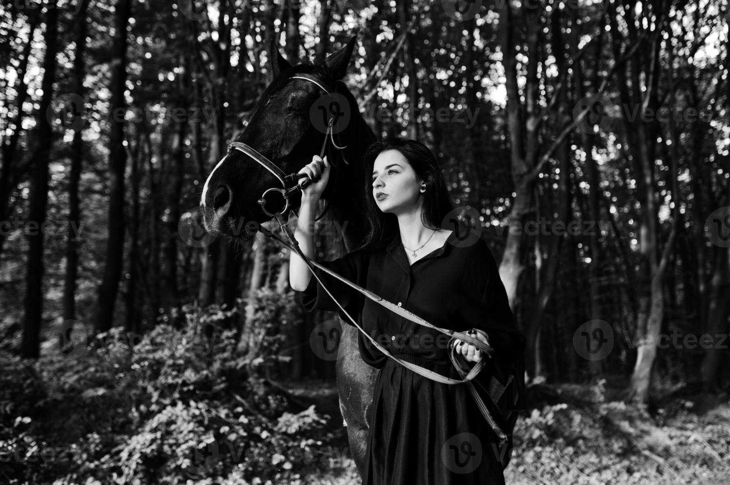 Mystical girl wear in black with horse in wood. photo