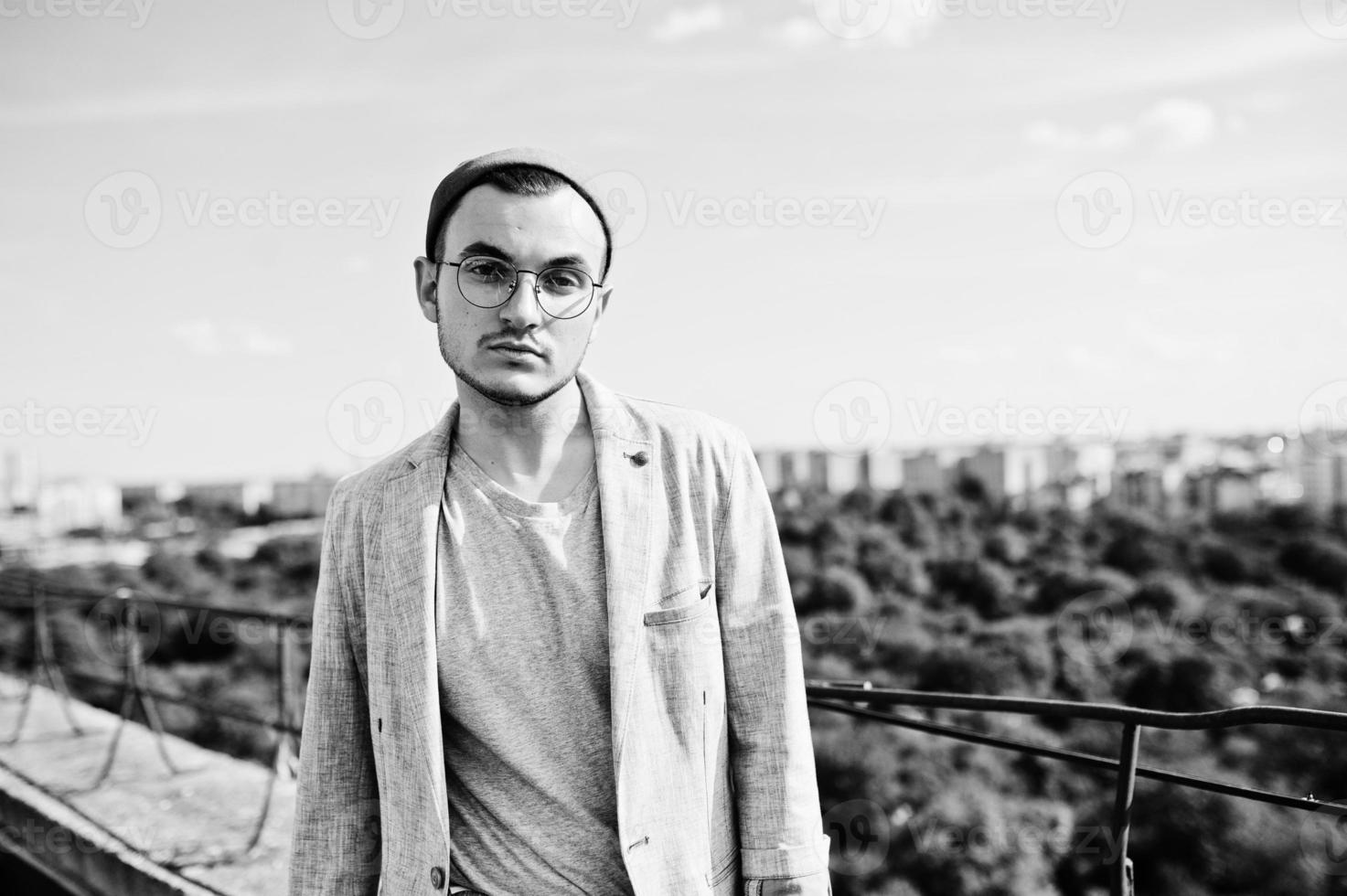 Dreamer stylish macho man in gray suit, hat and glasses posed on the roof. photo