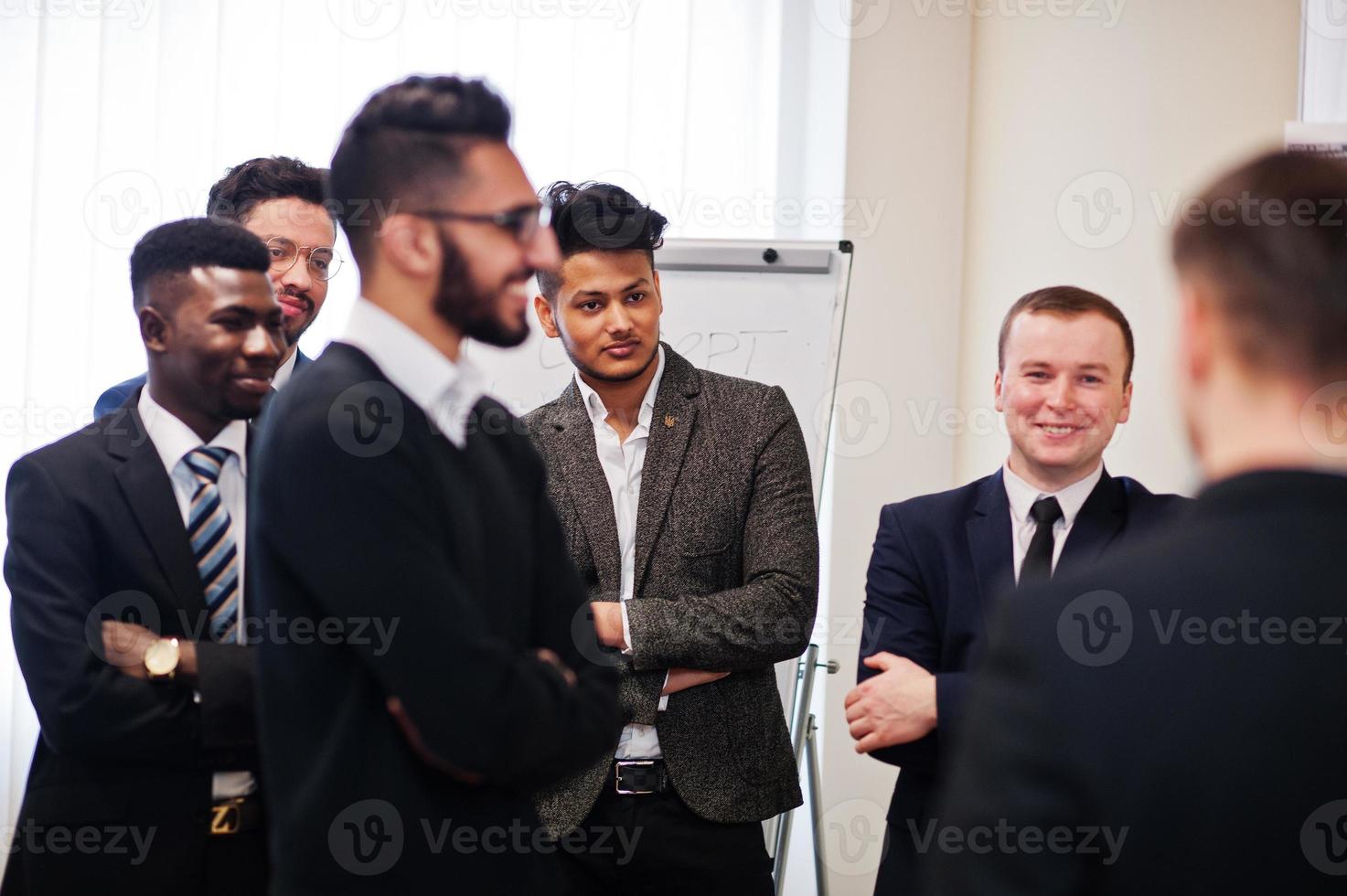 los colegas masculinos que trabajan en equipo cooperan, el equipo multirracial de empleados se concentra en la planificación de proyectos contra la junta y discute ideas. foto