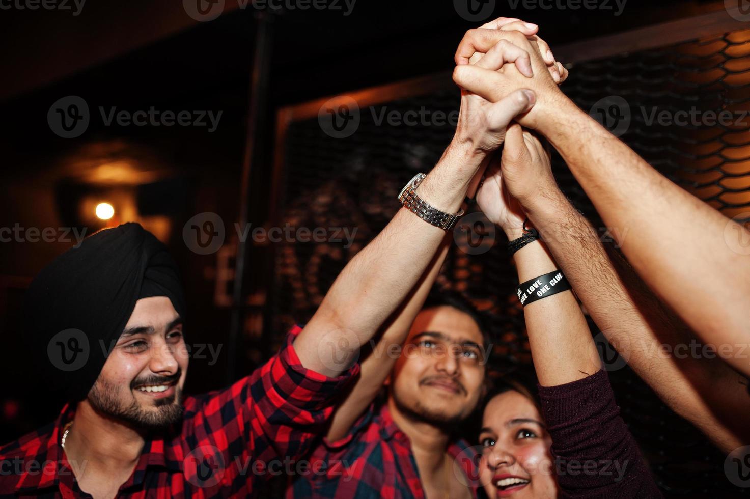 Group of indian friends having fun and rest at night club and giving high five together. photo