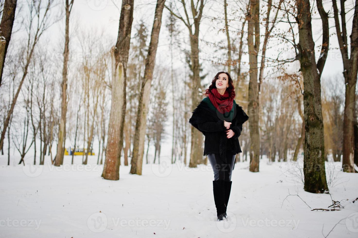 chica morena en suéter verde, abrigo y bufanda roja al aire libre en el día de invierno por la noche. foto