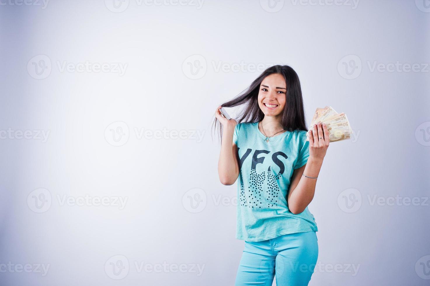 Portrait of an attractive girl in blue or turquoise t-shirt and trousers posing with a lot of money in her hand. photo