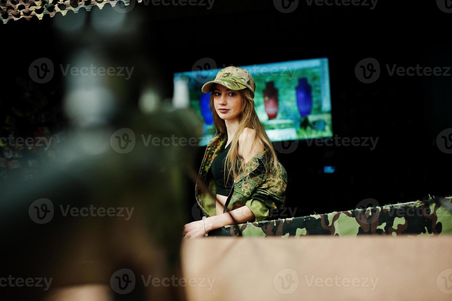 Military girl in camouflage uniform against army background on shooting range. Aim people. photo