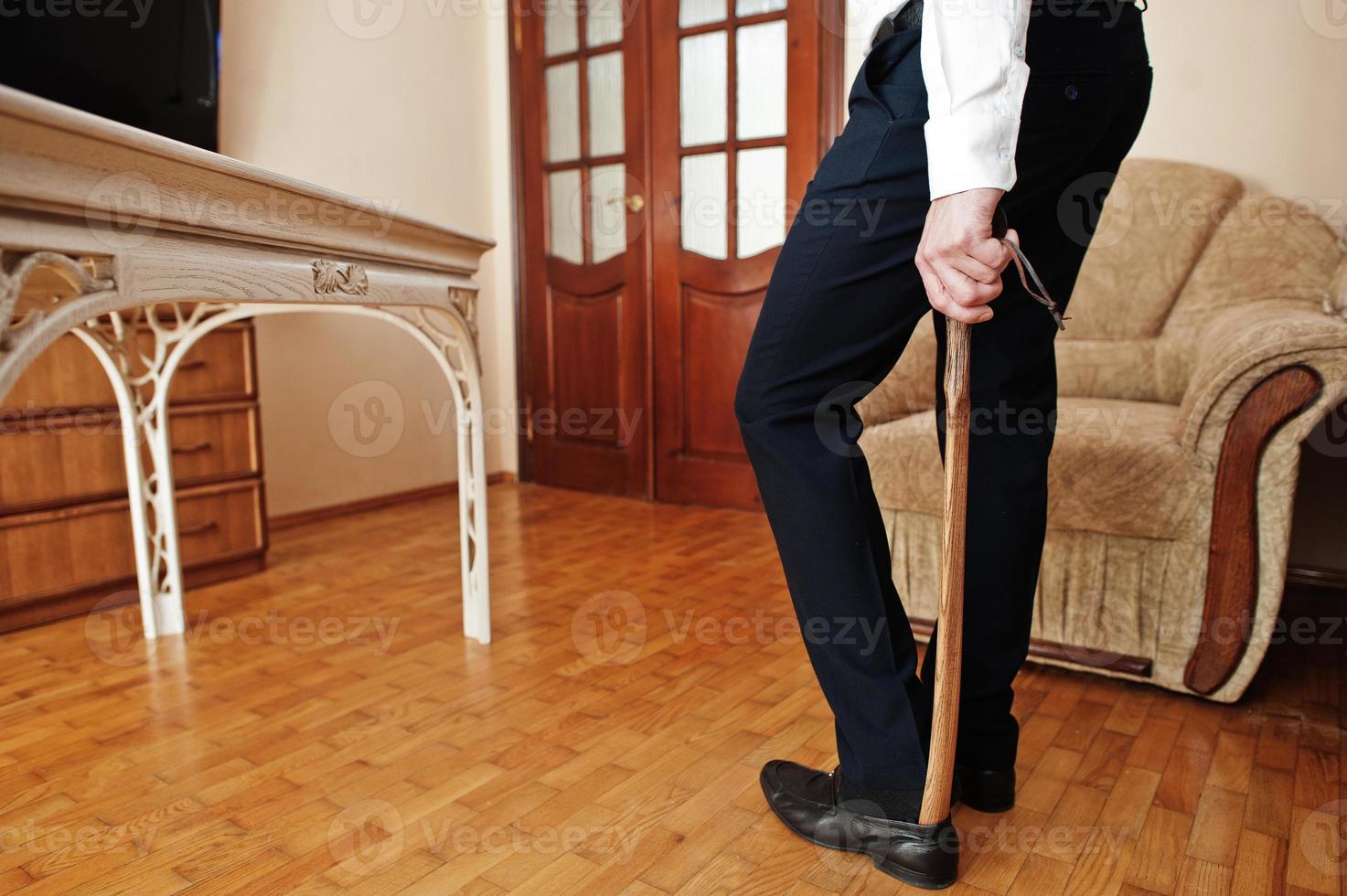 Man puts on classic black shoes with a wooden shoe spoon. photo