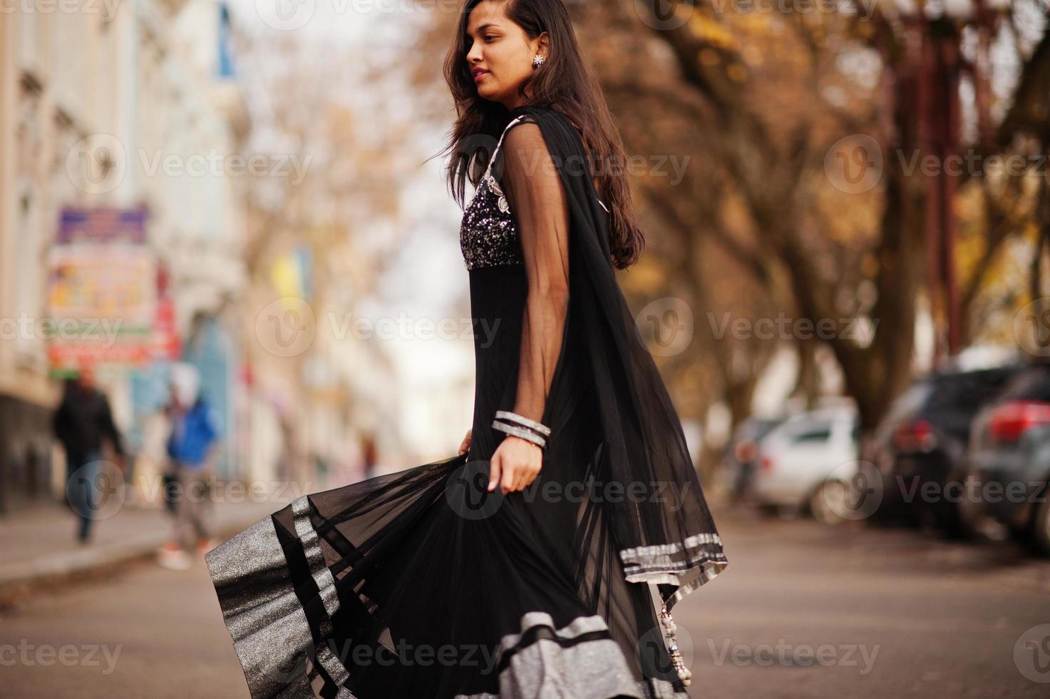 linda chica india con vestido de sari negro posó al aire libre en la calle de otoño. foto