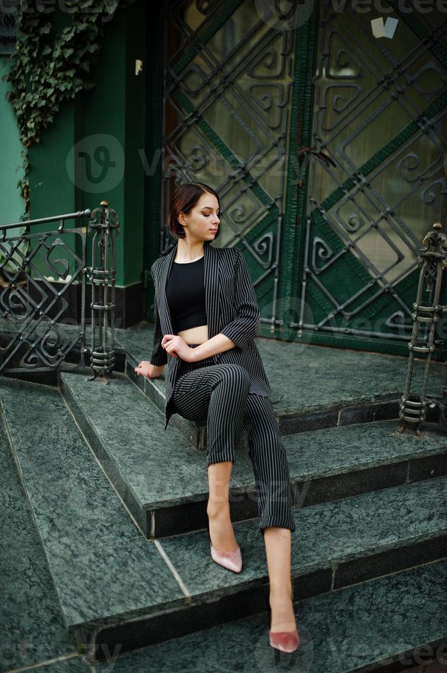 una mujer modelo hermosa y elegante joven de piernas largas en ropa formal posó en las escaleras. foto
