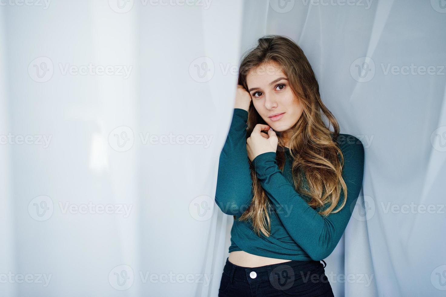 Handsome brunette girl wear on green, posing at curtains. Studio model portrait. photo