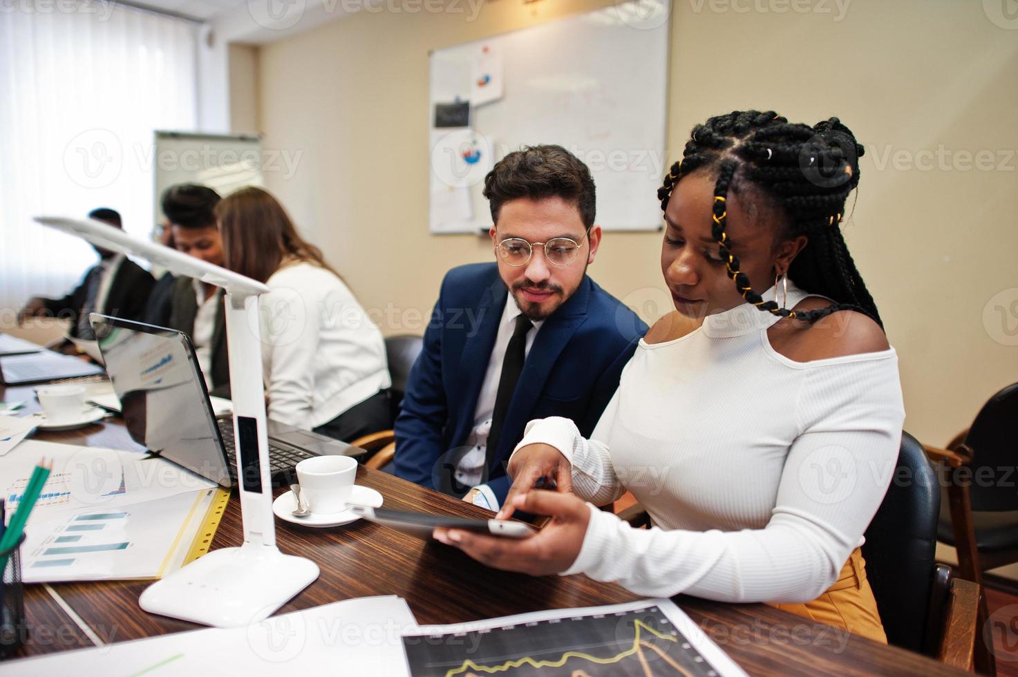 Multiracial business team addressing meeting around boardroom table. photo