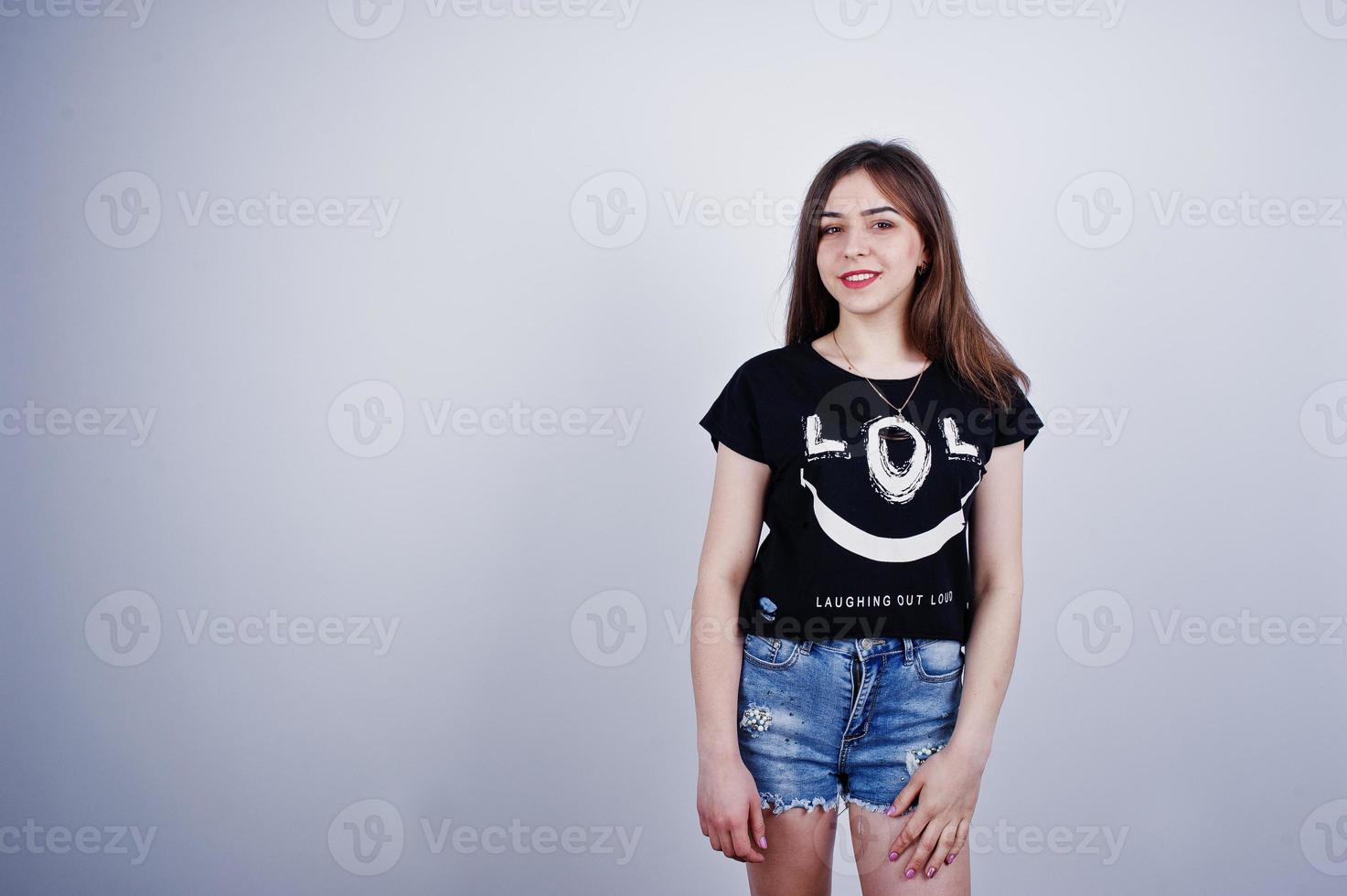 Portrait of an attractive girl in black t-shirt saying lol and denim shorts posing in the studio. photo