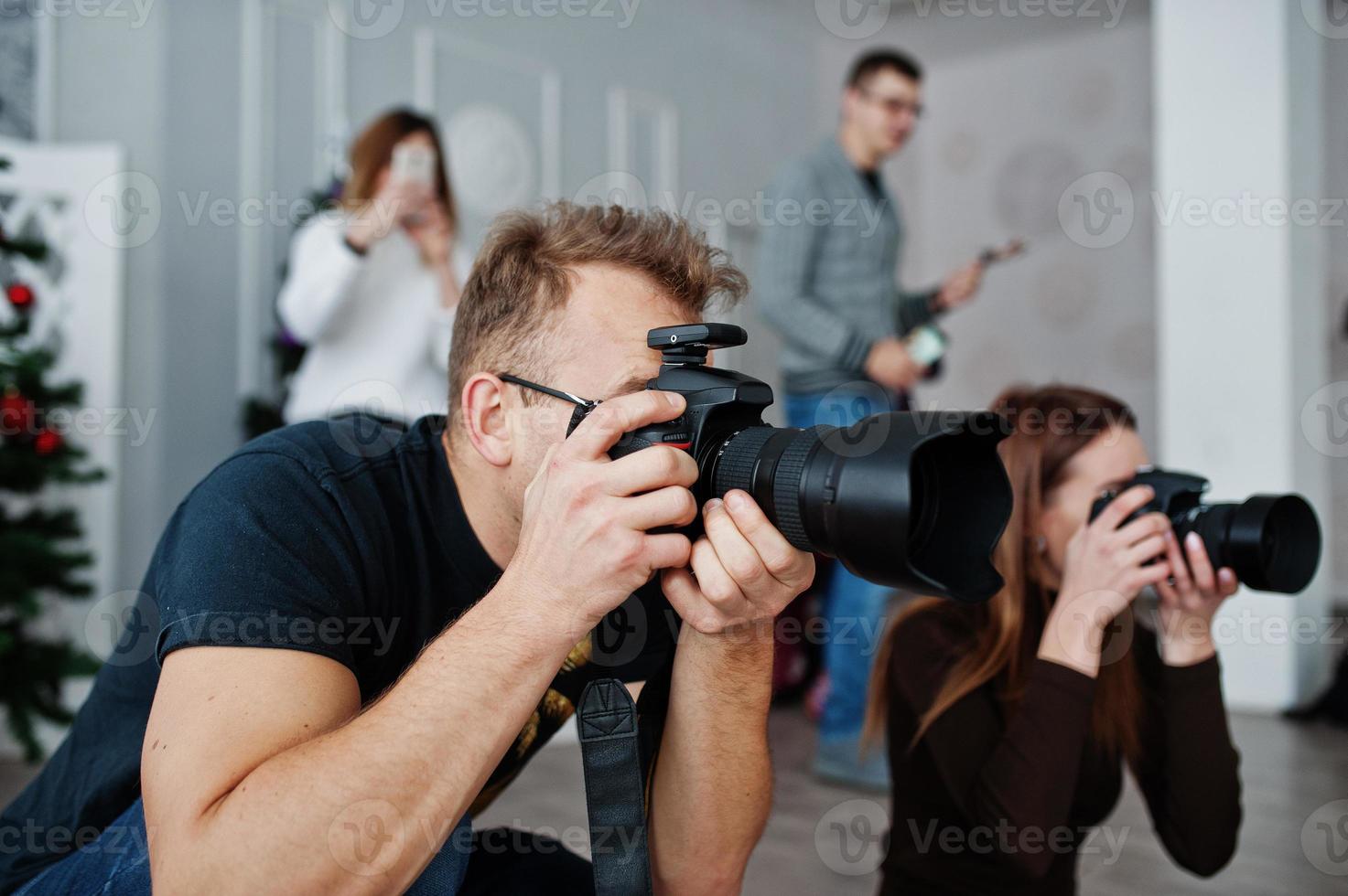 The team of two photographers shooting on studio behind another three workers. Professional photographer on work. Master class. photo