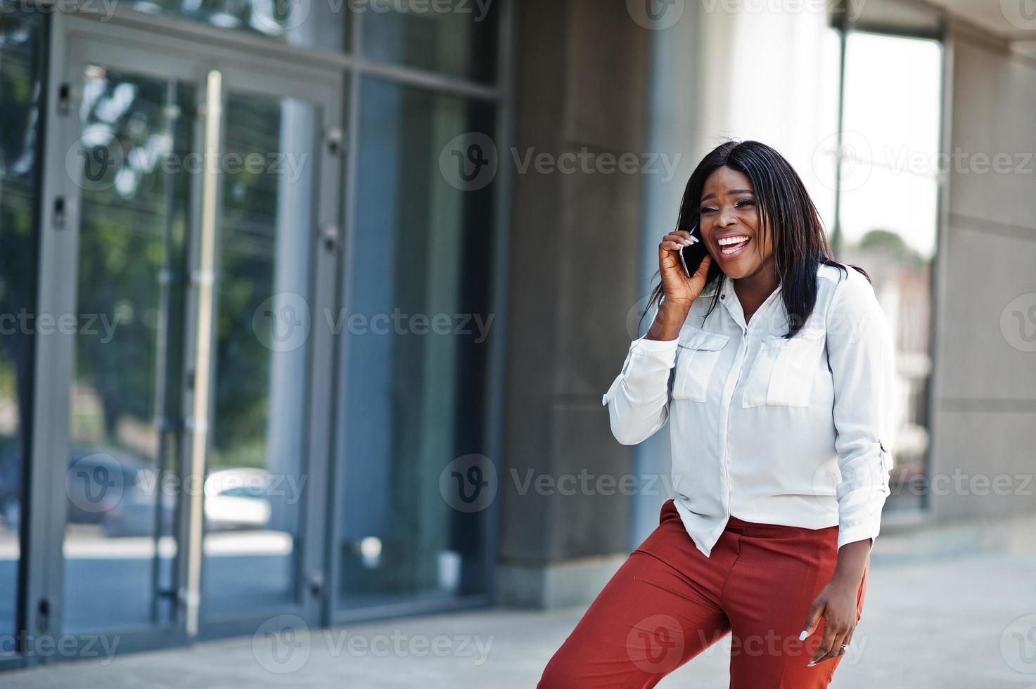 Mujer de afroamericana vestida formalmente con blusa blanca y pantalón rojo con teléfono móvil. exitosa empresaria de piel oscura. 10441938 Foto de stock en