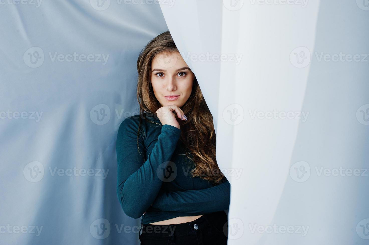 Handsome brunette girl wear on green, posing at curtains. Studio model portrait. photo
