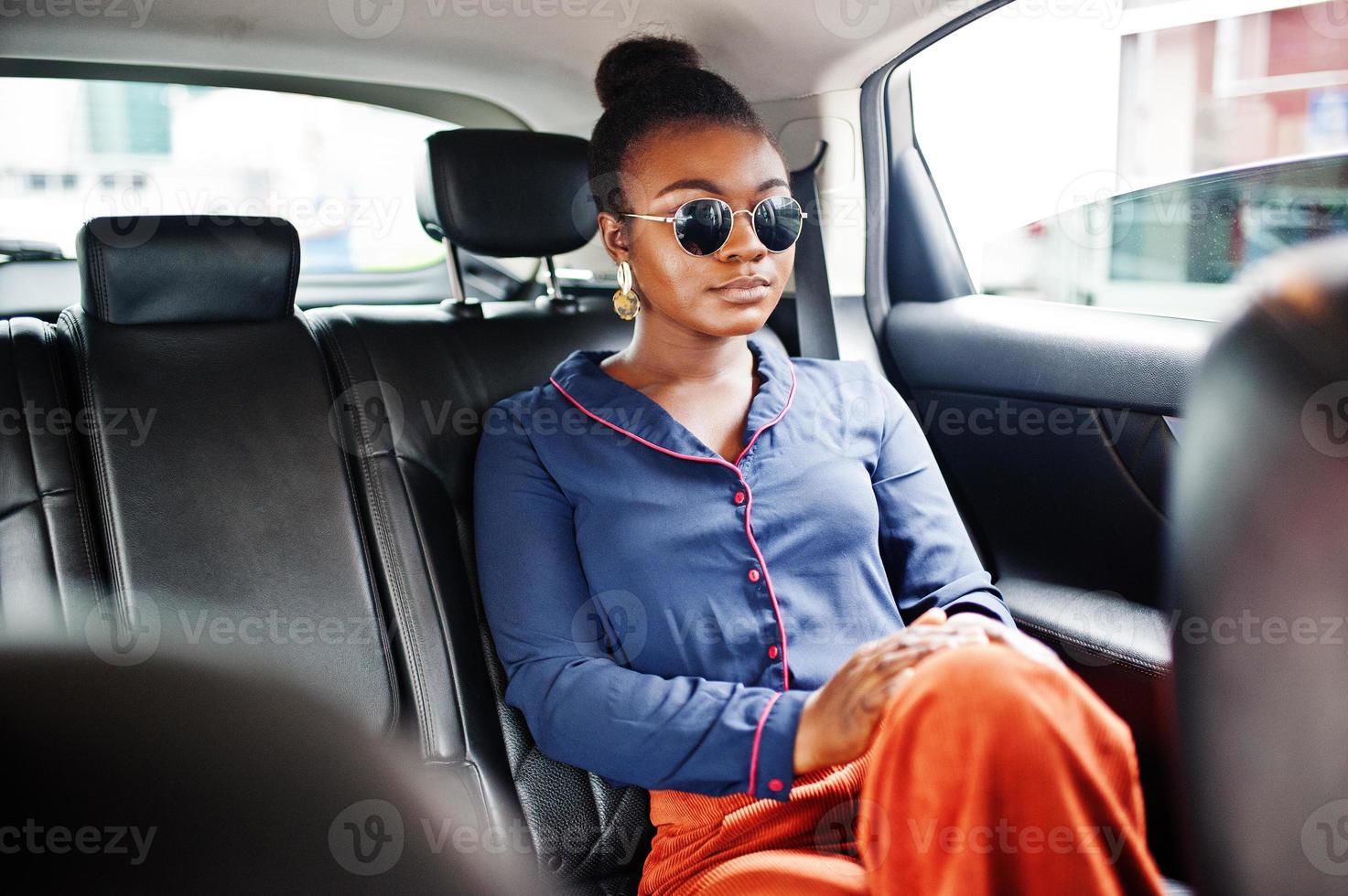 una rica mujer africana de negocios con gafas de sol se sienta en un camión suv con asientos de cuero negro. foto