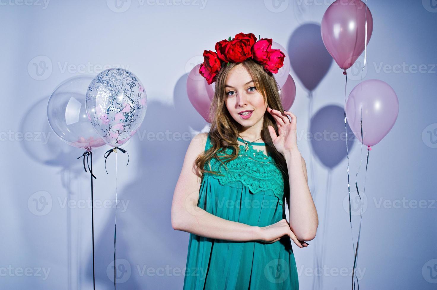 Happy girl in green turqoise dress and wreath with colored balloons isolated on white. Celebrating birthday theme. photo