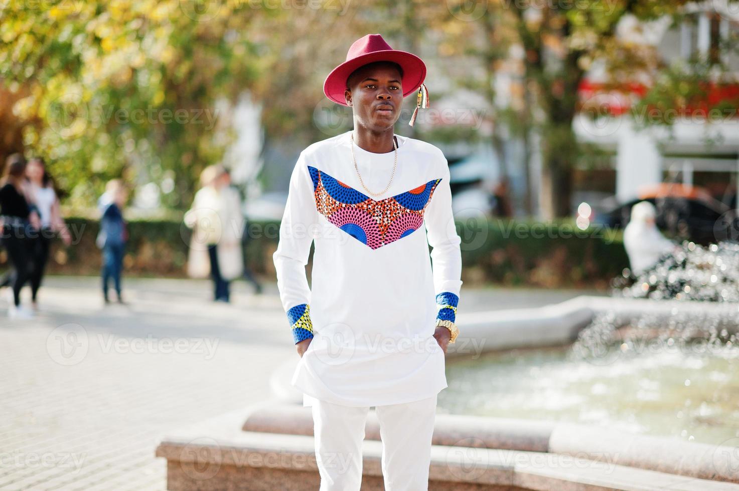 Stylish trendy afro france man in red hat and white outfit posed at autumn day. Black african model guy. photo