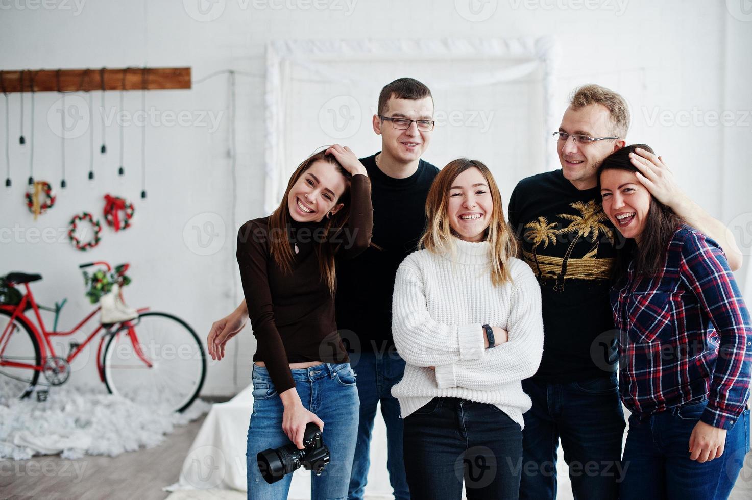 grupo de cinco personas, amigos fotógrafos y diseñadores en estudio después de un duro día de trabajo. ellos felices y riendo. foto