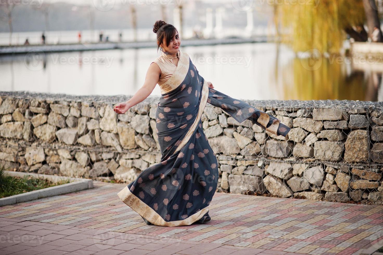 elegante morena chica india del sur de asia en sari bailando al aire libre. foto