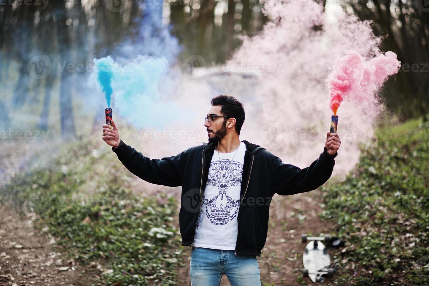 Street style arab man in eyeglasses hold hand flare with red and blue smoke grenade bomb. photo