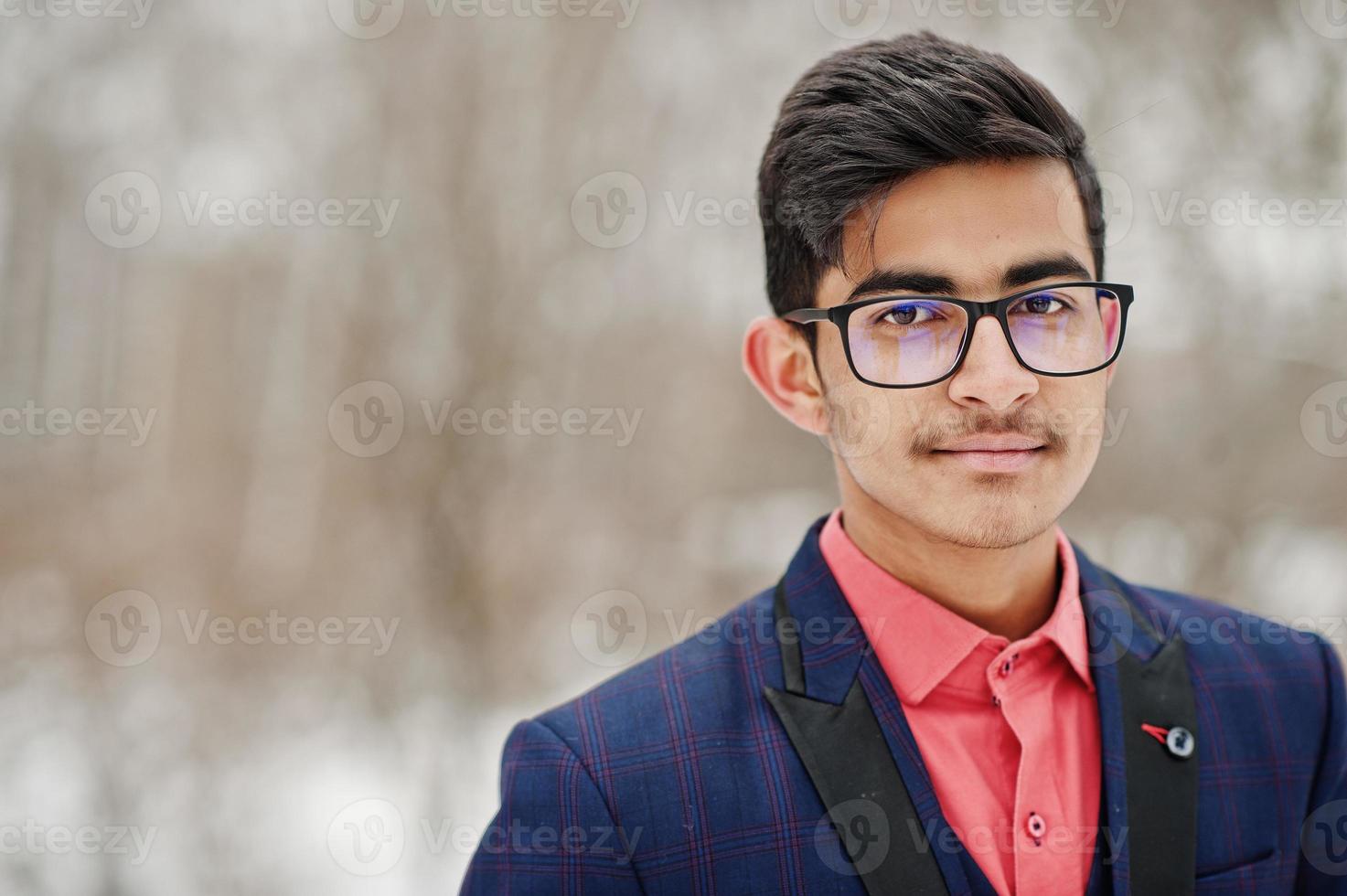 primer plano retrato de un elegante estudiante indio con traje, gafas posadas en el día de invierno al aire libre. foto