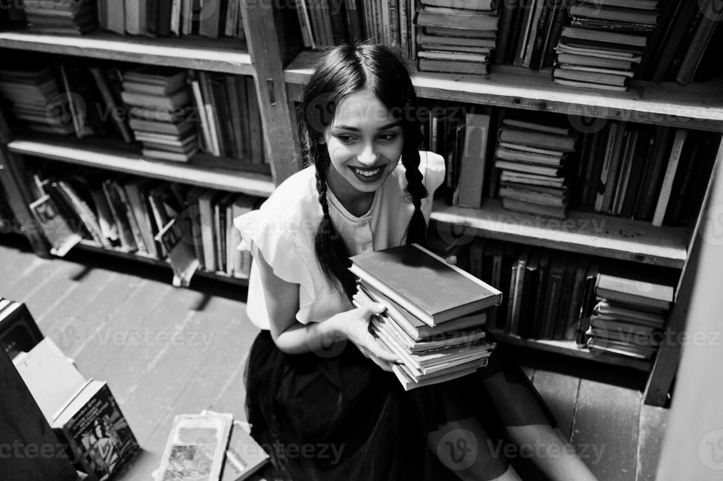 Girl with pigtails in white blouse at old library. photo