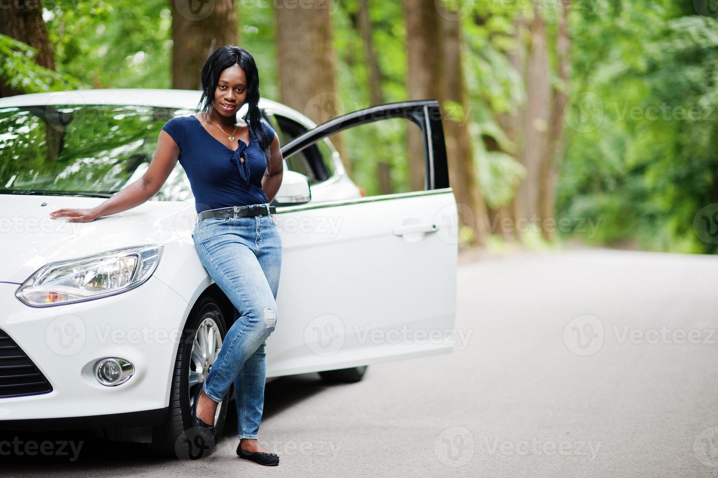 African american woman posed against white car in forest road. photo