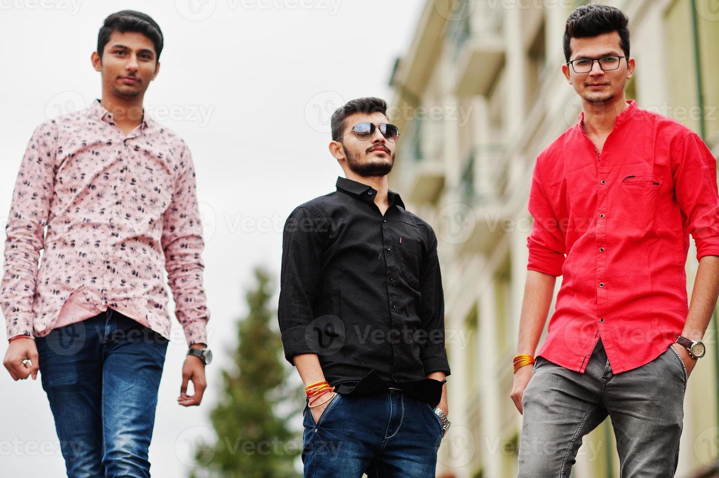 Three indian guys students friends walking on street. photo