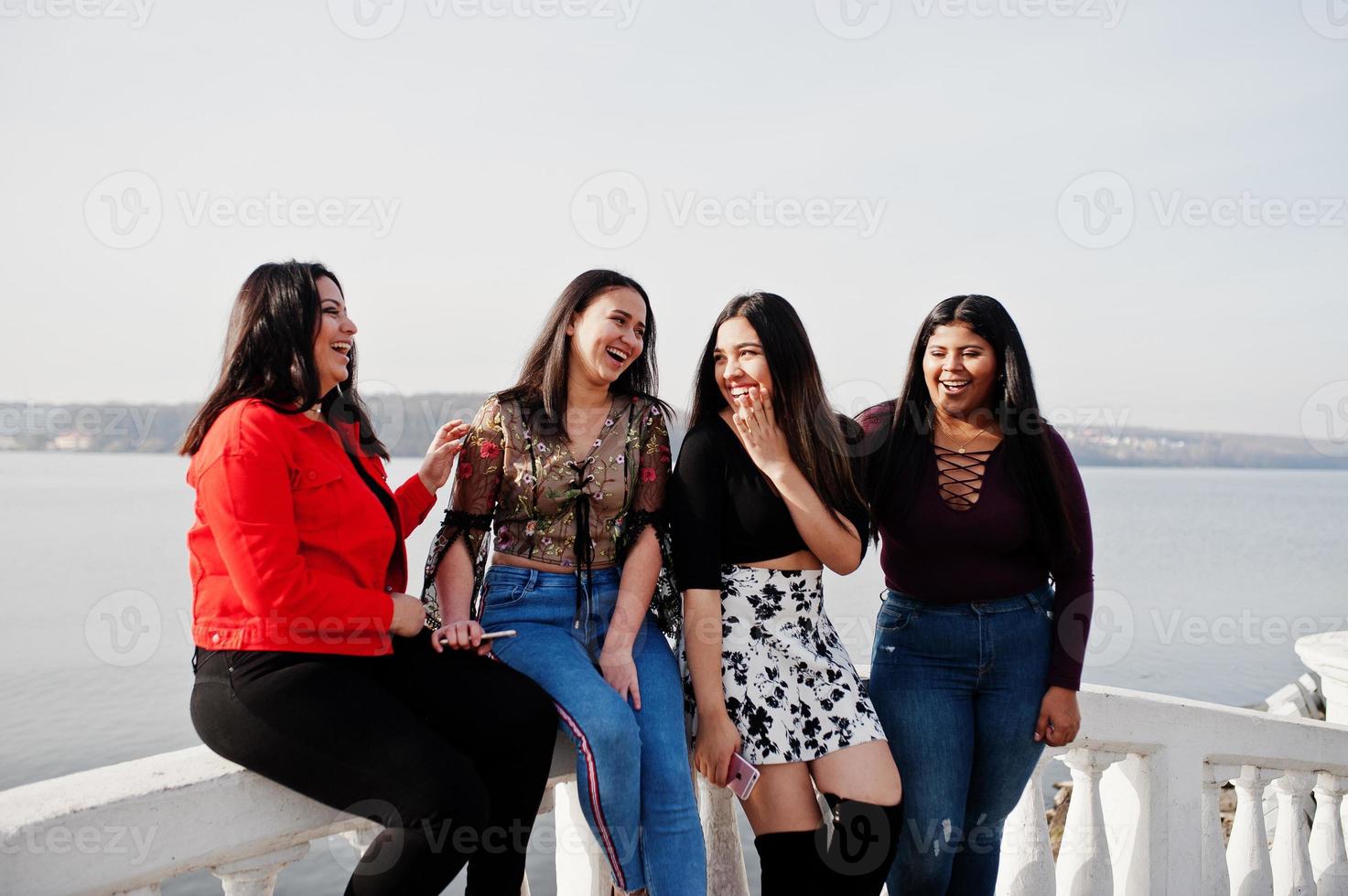grupo de cuatro chicas latinas felices y bonitas de ecuador posaron contra el lado del lago. foto