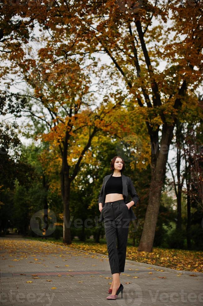 A tall leggy young beautiful and elegant model woman at formal wear posed at autumn background. photo