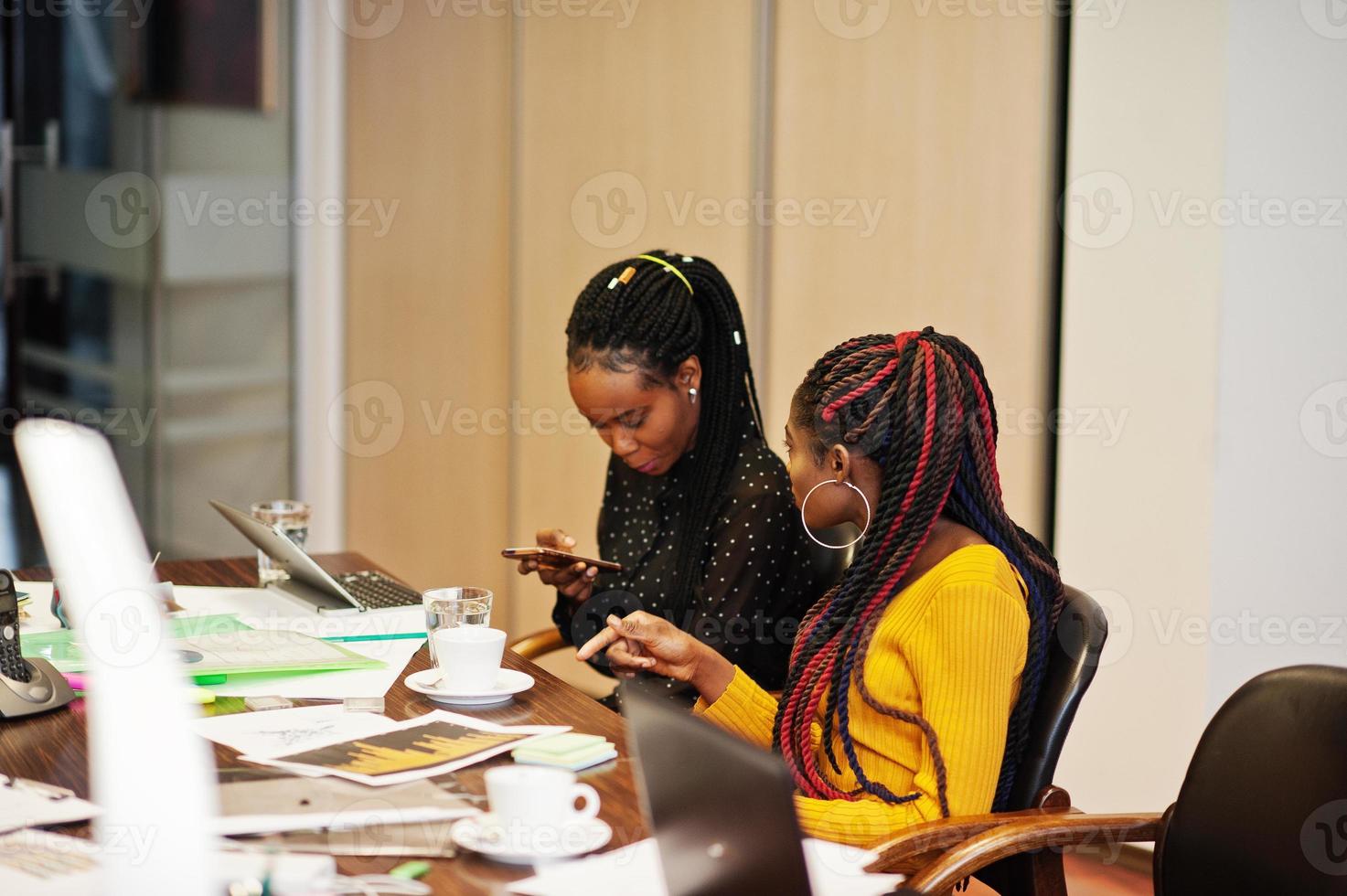 African american women colleagues, crew of divercity female partners in office sit at the table. photo