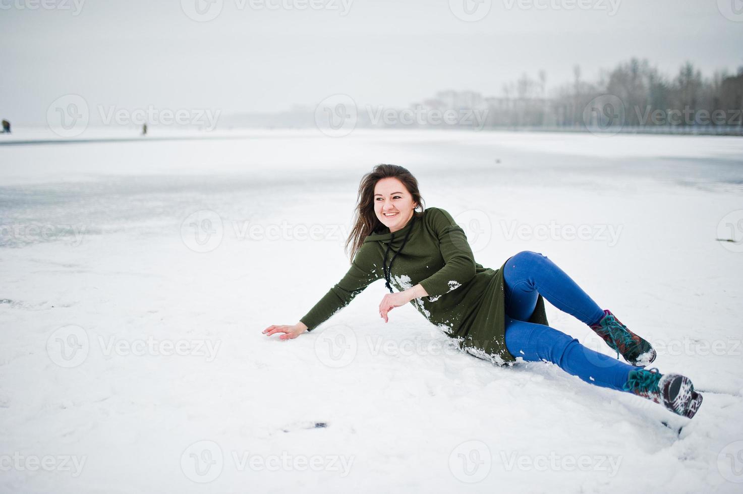 Funny girl wear on long green sweatshirt and jeans, at frozen lake in winter day. photo