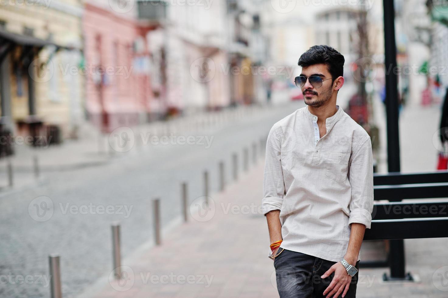 Stylish indian model man in casual clothes and sunglasses posed outdoor at street of India. photo