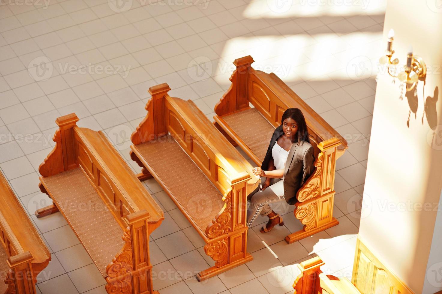 mujer afroamericana rezando en la iglesia. los creyentes meditan en la catedral y tiempo espiritual de oración. vista desde arriba. foto