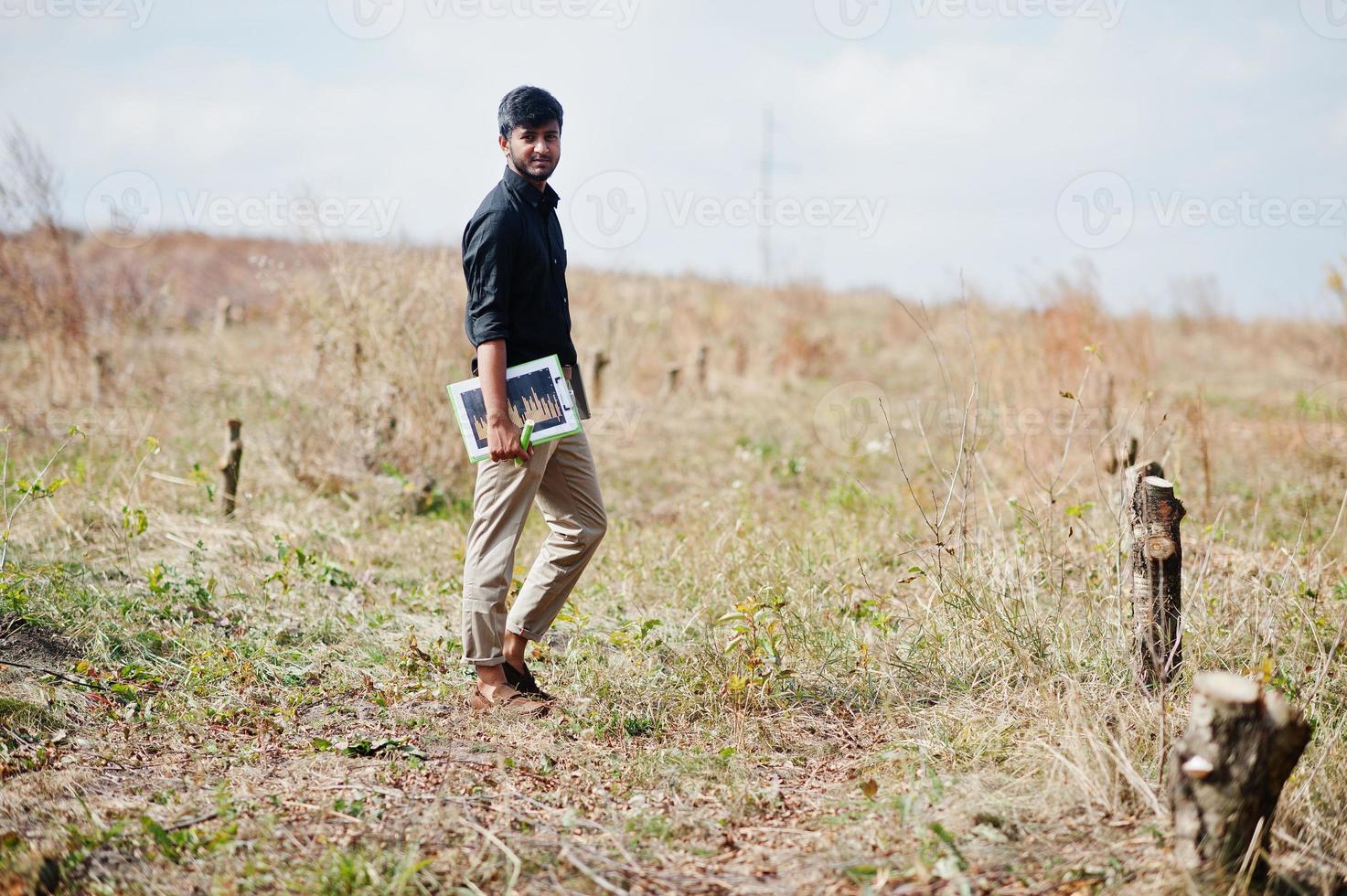 agricultor agrónomo del sur de asia con portapapeles inspeccionando árboles cortados en el jardín de la granja. concepto de producción agrícola. foto