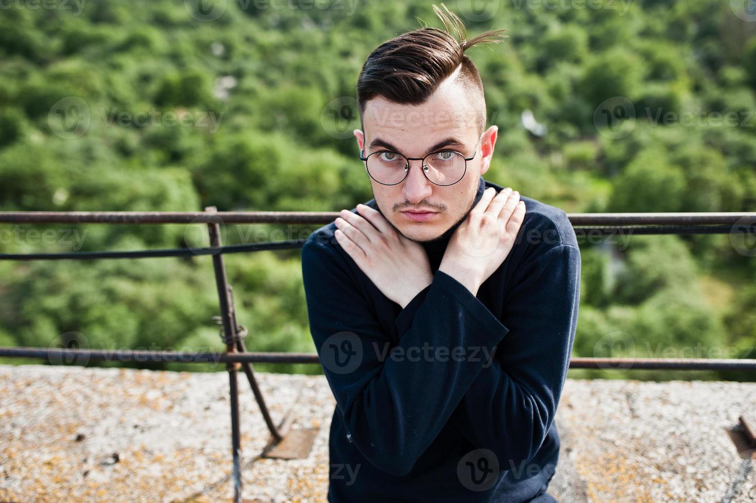 hombre macho con estilo soñador en golf negro y gafas posadas en el techo. foto