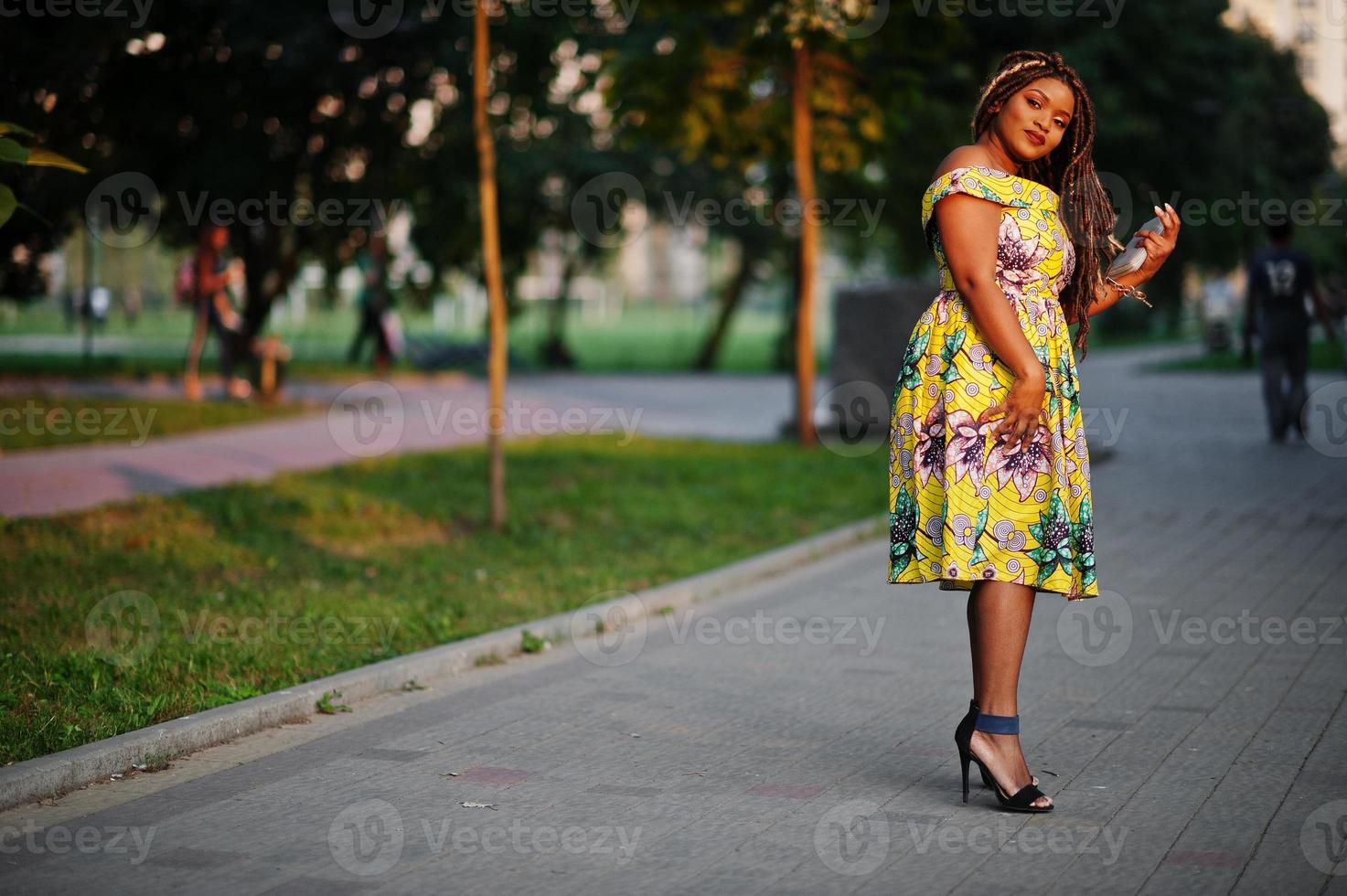 Cute small height african american girl with dreadlocks, wear at coloured yellow dress, posed at sunset. photo