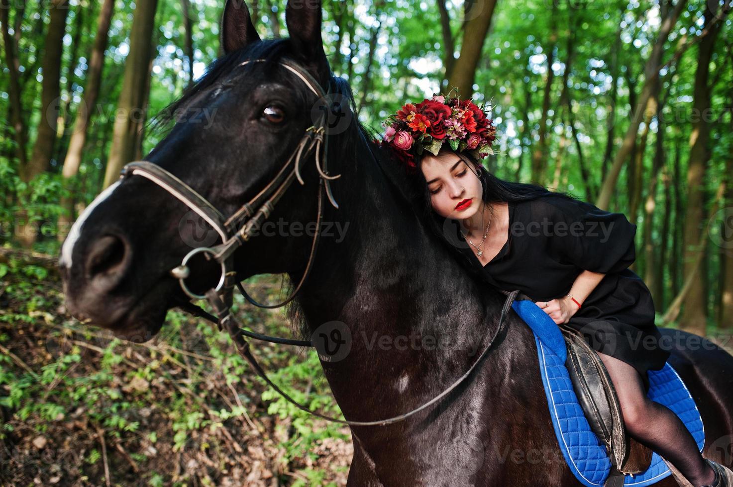 Mystical girl in wreath wear in black at horse in wood. photo