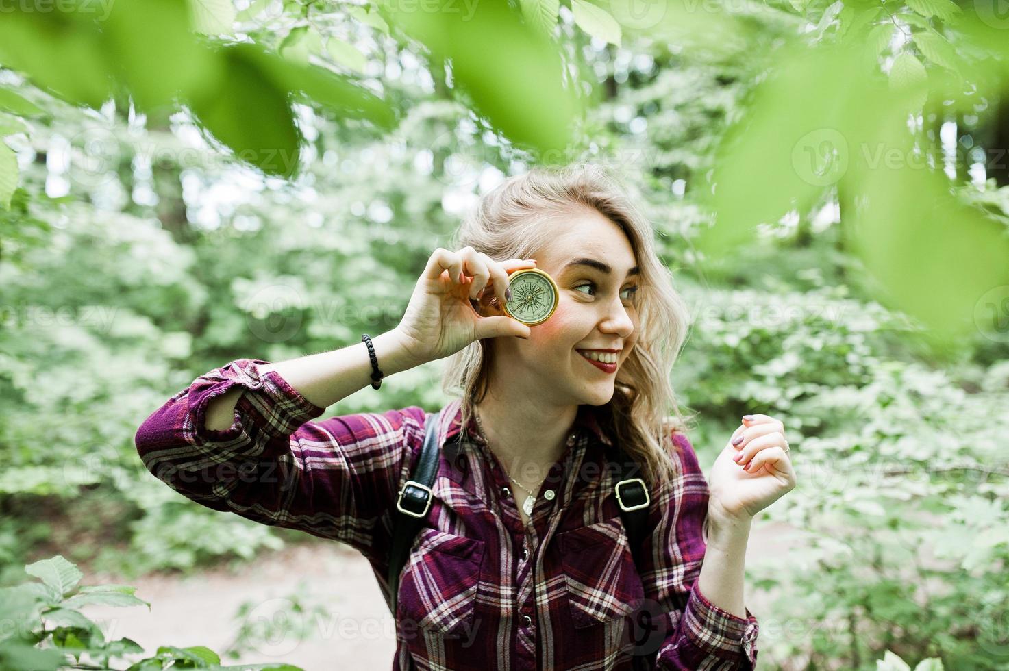 Portrait of an attractive blond girl posing with a compass in a forest. photo