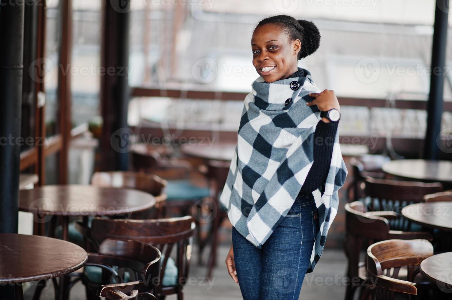 African woman in checkered cape posed outdoor cafe terrace. photo