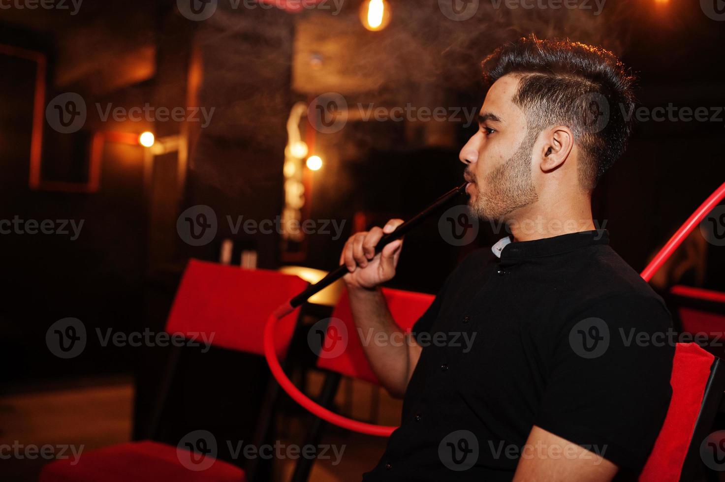 Asian man smoke hookah and having rest at lounge bar. photo