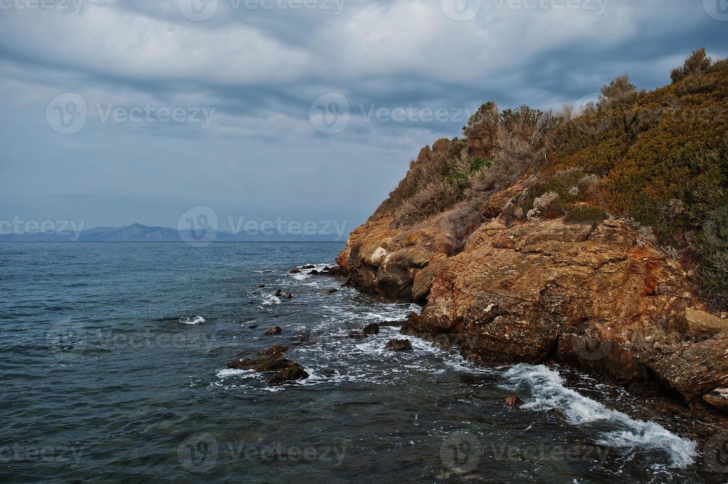 la ola del mar se rompe en el paisaje de rocas de la playa. las olas del mar chocan y salpican rocas en bodrum, turquía. foto