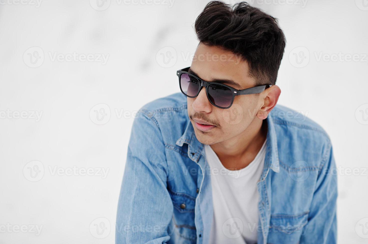 un joven indio casual con pantalones de mezclilla y gafas de sol posó en el día de invierno. foto