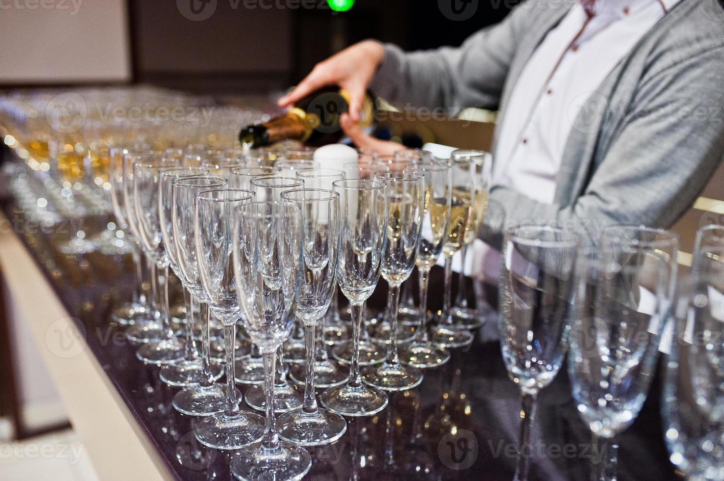 Barman or bartender pours alcohol into glasses in the restaurant. photo