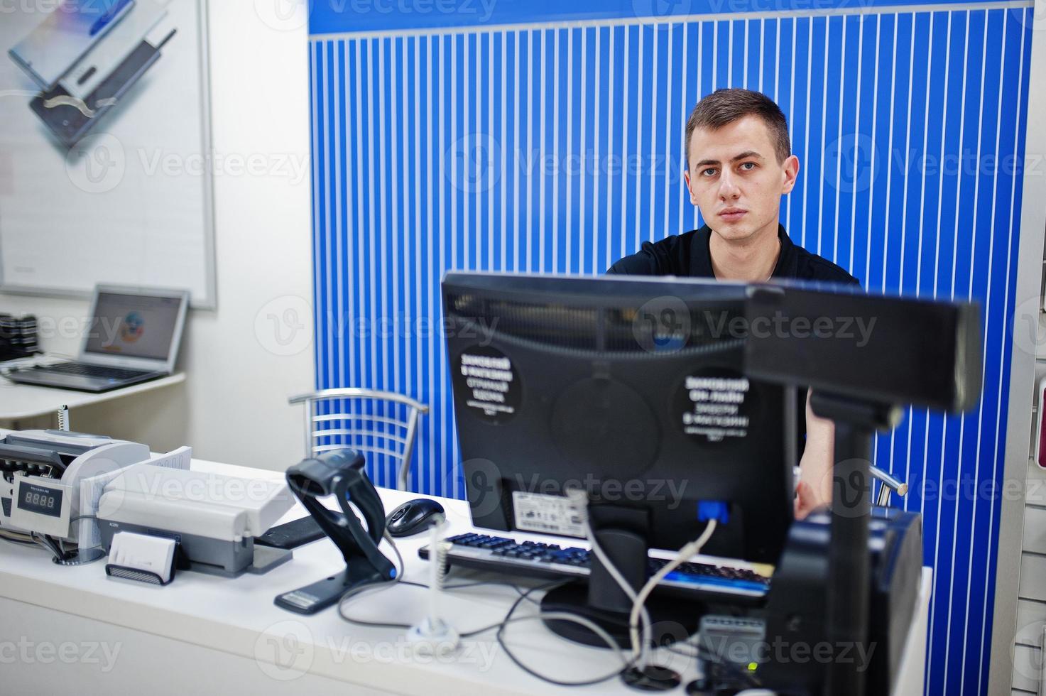 Seller man mobile phone professional consultant in tech store or shop works at the cashier. photo