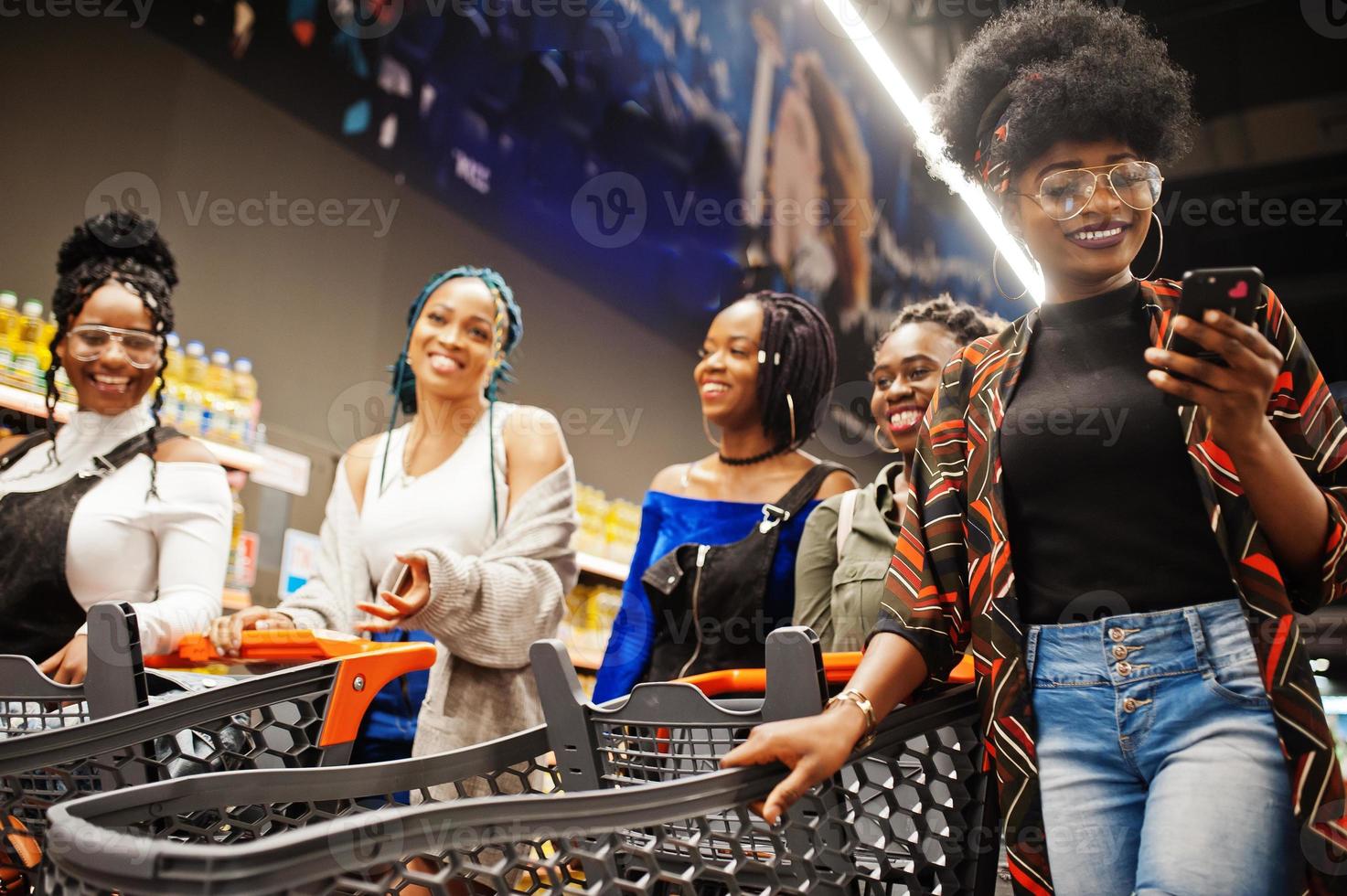 Group of five african womans walking in supermarket with shopping carts. photo