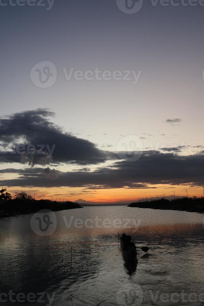 pescador en su barco al atardecer. barco de pescadores al atardecer foto