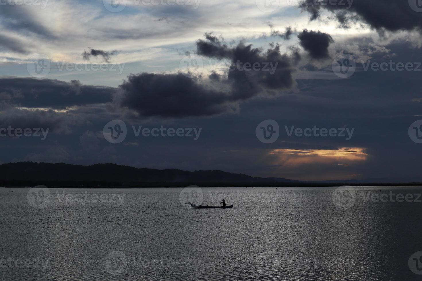 pescador en su barco al atardecer. barco de pescadores al atardecer foto