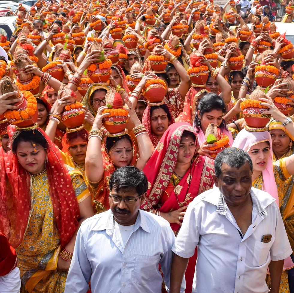 New Delhi, India April 03 2022 - Women with Kalash on head during Jagannath Temple Mangal Kalash Yatra, Indian Hindu devotees carry earthen pots containing sacred water with a coconut on top photo