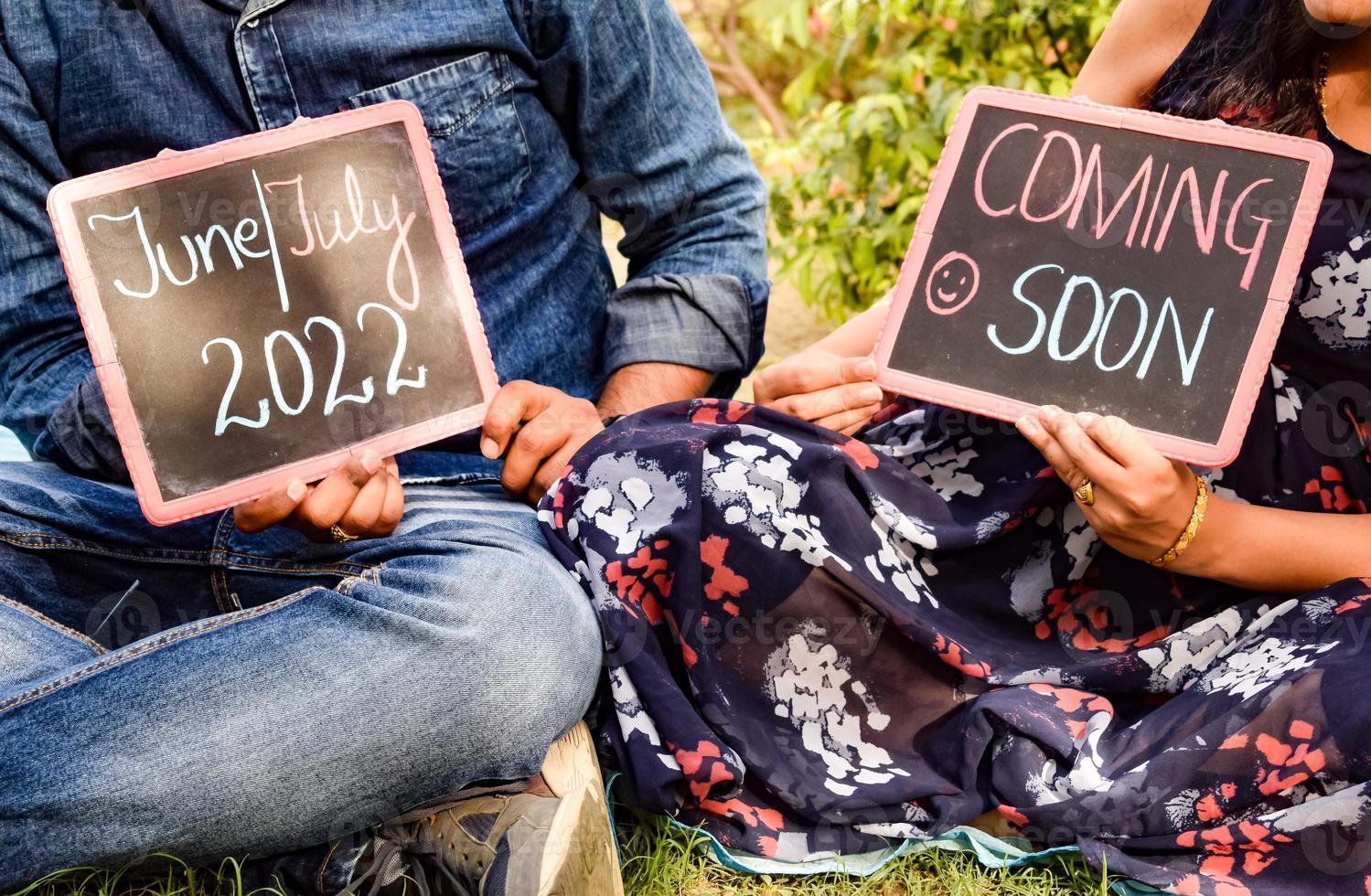 pareja india posando para una sesión de fotos de maternidad. la pareja está posando en un césped con hierba verde y la mujer está faluntando su panza en el jardín lodhi en nueva delhi, india